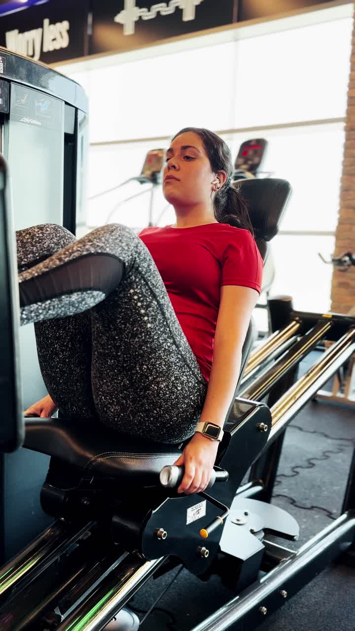 Young adult woman performing leg press exercise at the gym
