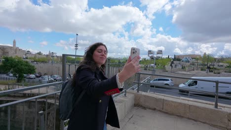 a woman is taking a picture of a cityscape with her cell phone. slow motion.