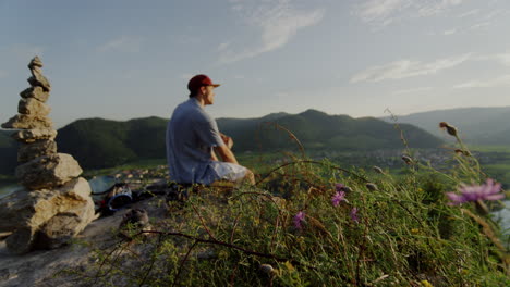 평화로운 산 피크닉 장소, 꽃 ⁇ 에서 휴식을 취하는 남자, 돌 탑, 전망을 즐기고, 전망을 즐기고, 풍경 개요, 영화 속도 느린 슬로모, 남자는 야외 언덕을 즐긴다