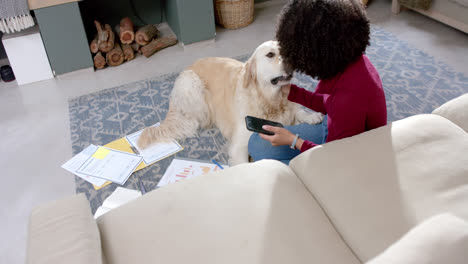 Mujer-Birracial-Con-Perro-Golden-Retriever-Usando-Un-Teléfono-Inteligente-En-Casa,-Cámara-Lenta