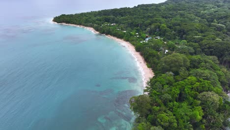 Aerial-footage-of-a-sandy-beach-nestled-within-a-bay-in-Puerto-Viejo,-Costa-Rica