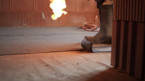 contractor worker flaming roofing hydro insulation sheet layer felt with a propane gas burner welding torch bitumen at construction site