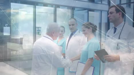 network of connections against male doctor shaking hands with medical professionals at hospital