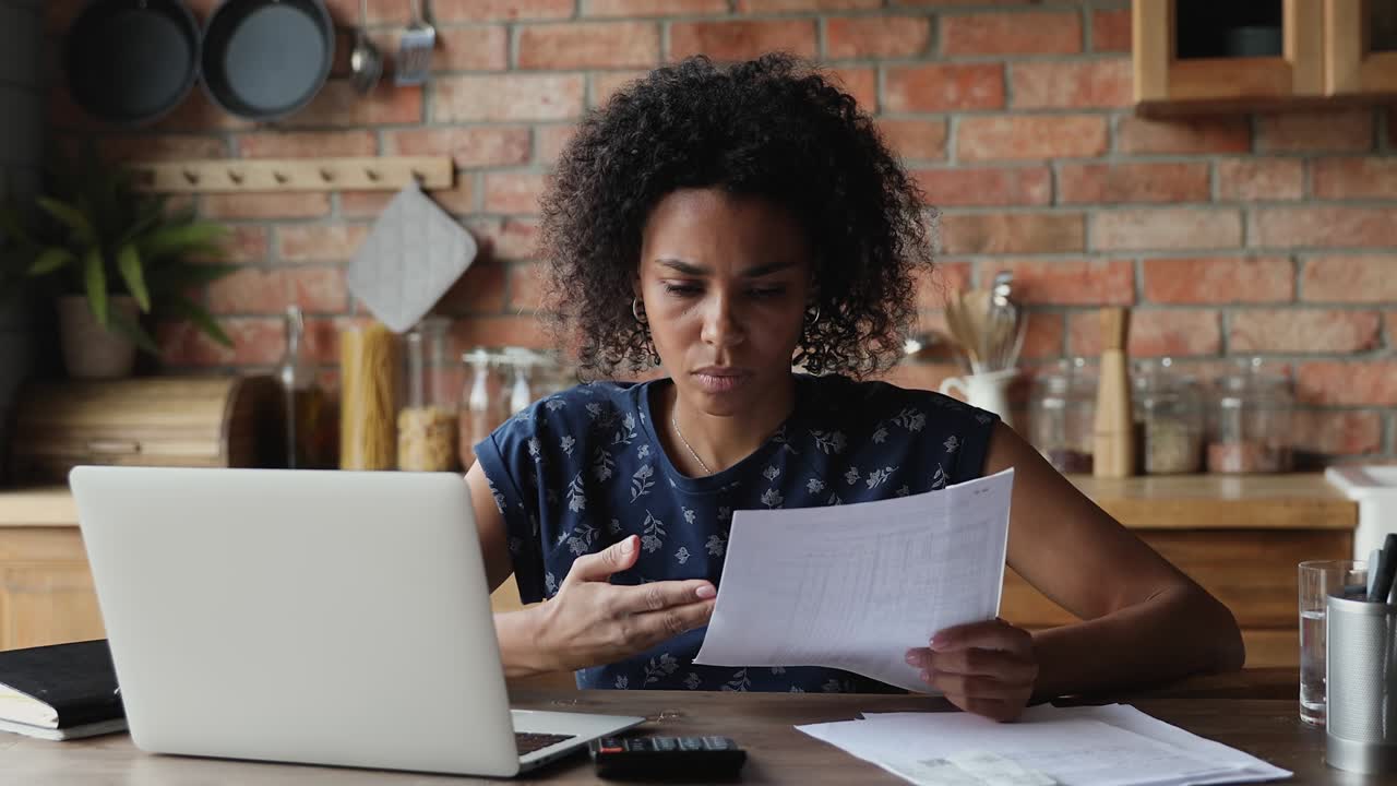 mujer negra estresada maneja documentos financieros encuentra facturas atrasadas