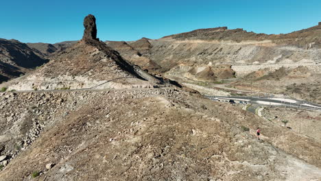 long-haired-young-woman-descends-mountain-and-moving-away-from-rocky-mountain-located-on-the-island-of-Gran-Canaria