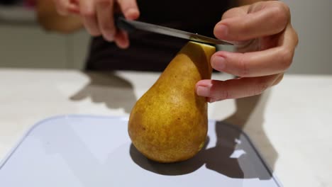 person slicing a pear with a knife