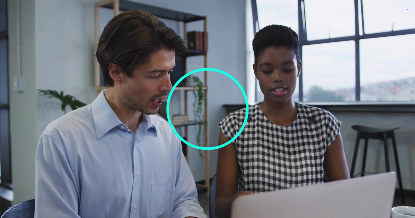 Woman gesturing at desk, man navigating laptop with animated chart for business project review