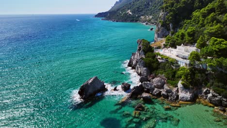 drone view of rocky coastline with turquoise sea and lush trees