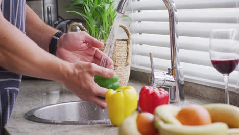 Video-of-hands-of-caucasian-man-washing-pepper-in-kitchen