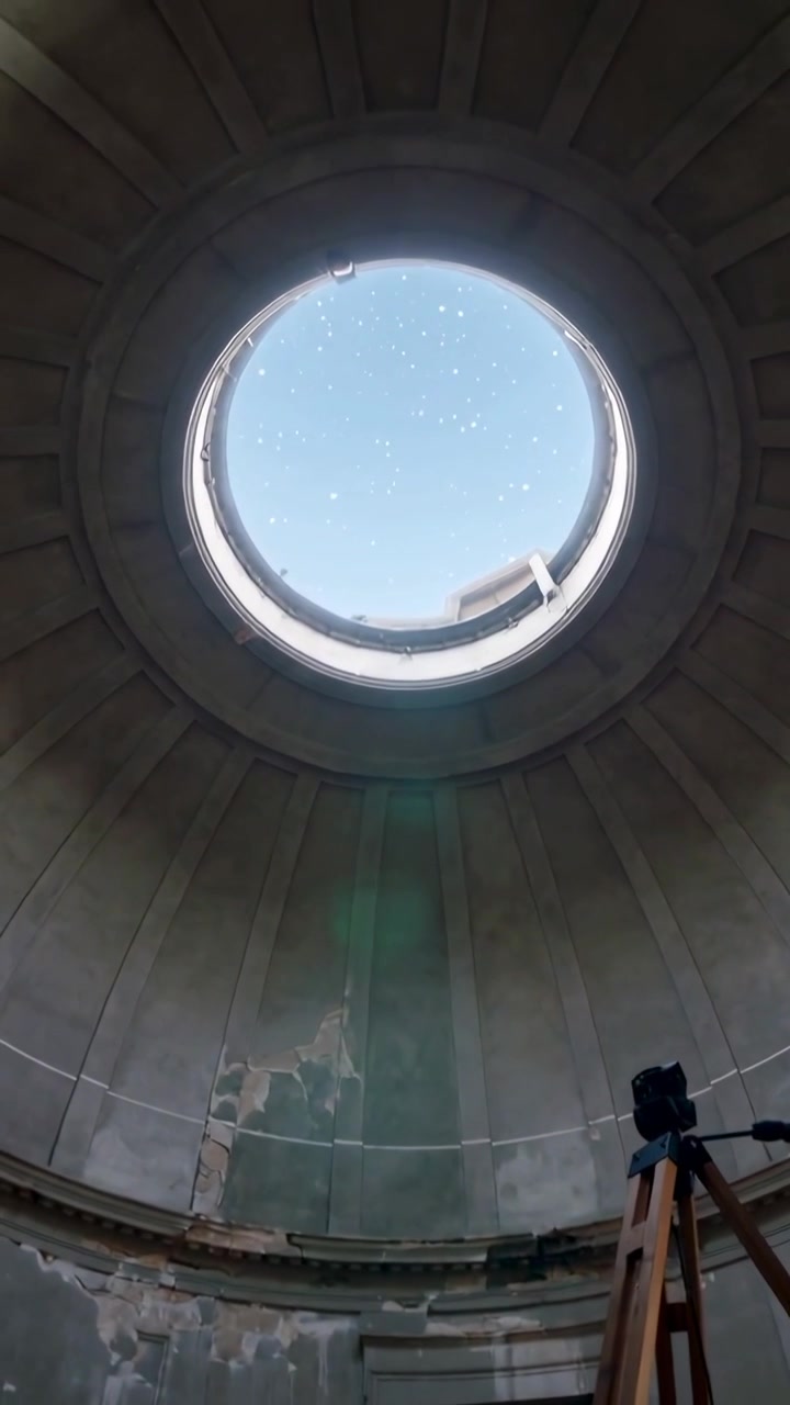 Video verticale: Inquadratura di un oculo che mostra il cielo in una rotonda mentre l'esposizione cambia, con treppiede e bagliore verde.