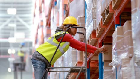 male warehouse worker using ladder to arrange cardboard box