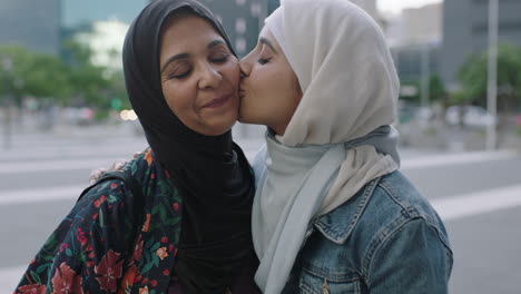 portrait of muslim family in urban city daughter kisses mother on cheek showing affection wearing traditional headscarf