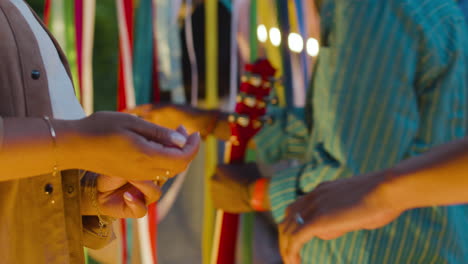 una mujer se pone una pulsera a un hombre.