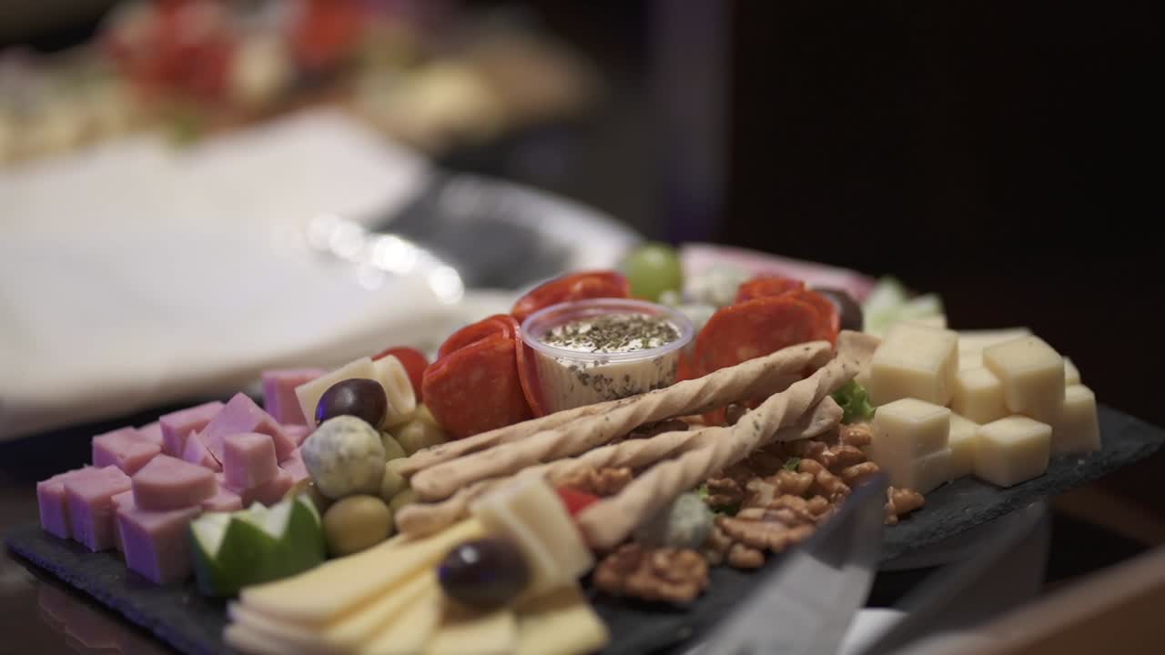elegante plato de aperitivo, tablero de charcutería con una variedad de quesos y otros aperitivos, perfecto para cenas de negocios o cualquier evento especial - de cerca