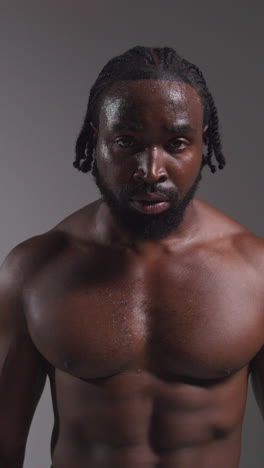 retrato de estudio de cerca de un boxeador masculino respirando fuertemente después de un partido de boxeo o entrenamiento contra un fondo gris