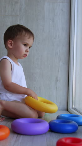 toddler playing with colorful rings by the window
