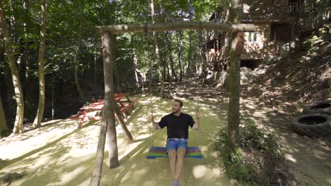 young man swinging on swing, slow motion.