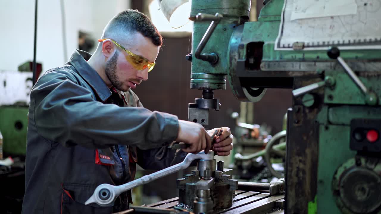 Worker in factory at machine. Worker in protective clothing in factory using machine