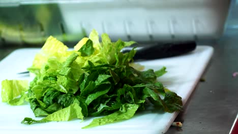 Chef-Chopping-fresh-green-lettuce-on-kitchen-restaurant-table