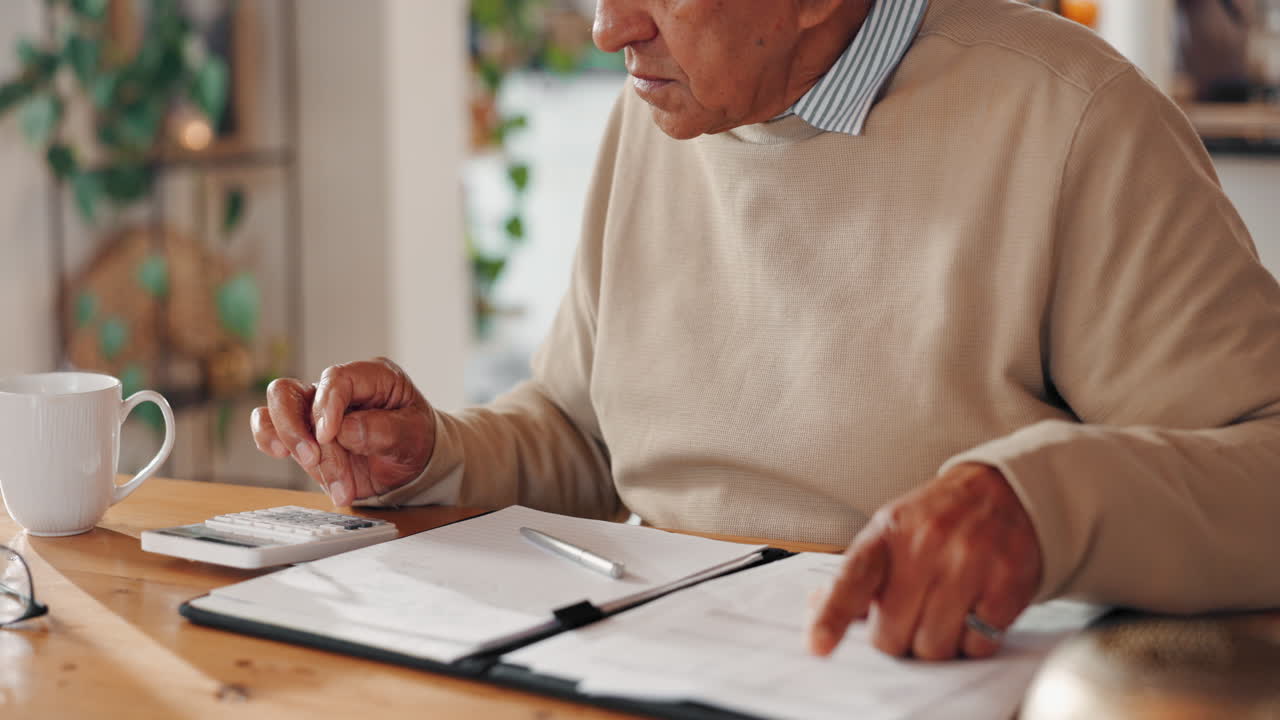 un hombre mayor está sentado en una mesa pagando cuentas.