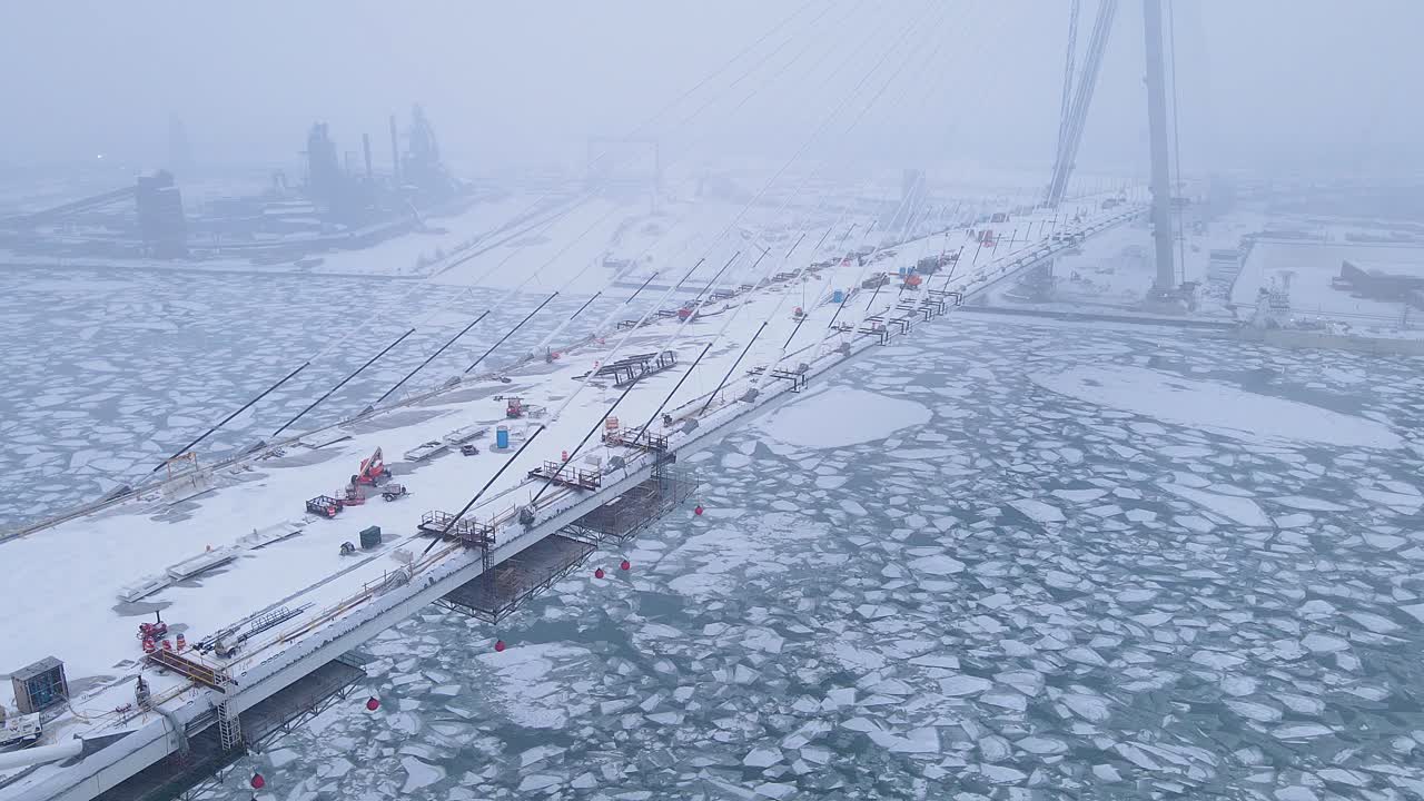 Foggy view of Gordie Howe Bridge under construction above frozen Detroit river