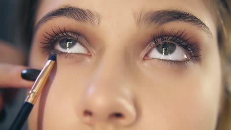 Close-Up-view-of-professional-makeup-artist-hands-using-makeup-brush-to-apply-eye-shadows.-Slow-Motion-shot