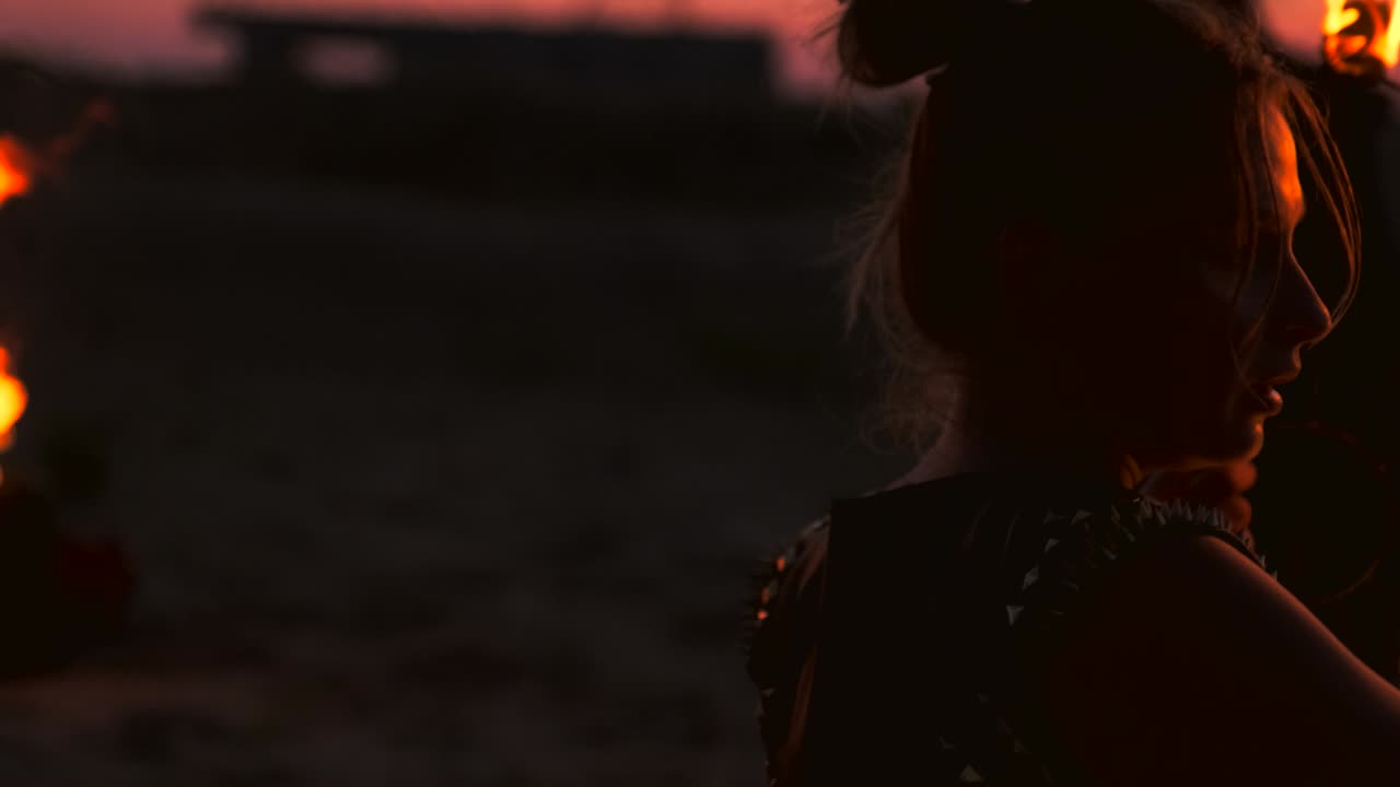 un grupo de hombres y mujeres muestran fuego por la noche en la arena