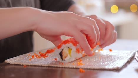 fare il sushi in cucina. mani di donna che arrotolano il sushi fatto in casa.