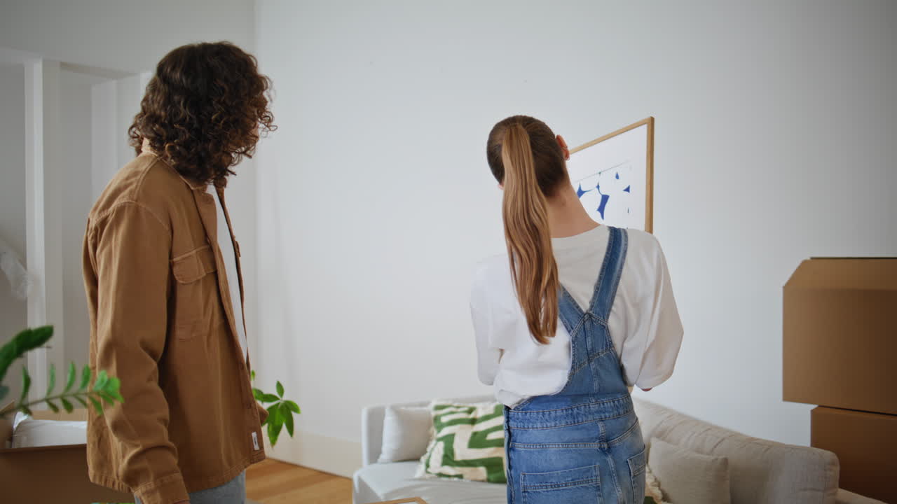 Young couple discussing artwork in bright living room closeup. Man looking woman
