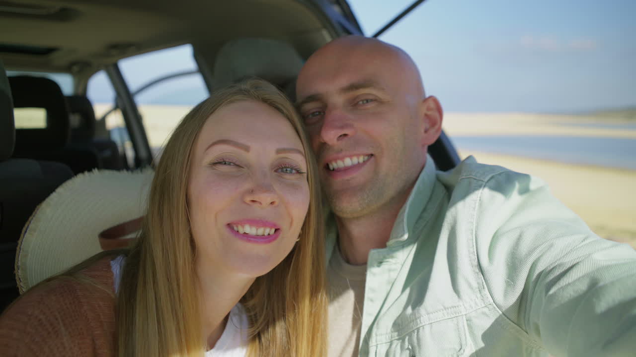 una pareja feliz tomando selfies en el coche.