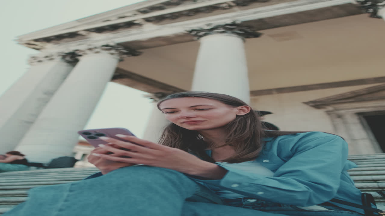 Giovane donna sorridente mentre usa lo smartphone all'aperto