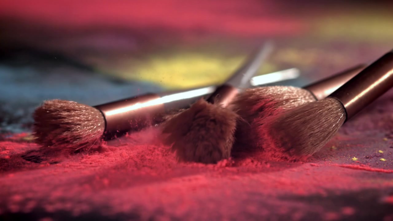 Makeup Brushes Falling onto Colorful Powder in Slow Motion