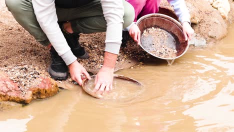 two people panning for gold in water