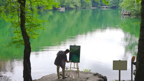 Painter-painting-against-lake-and-forest-landscape.