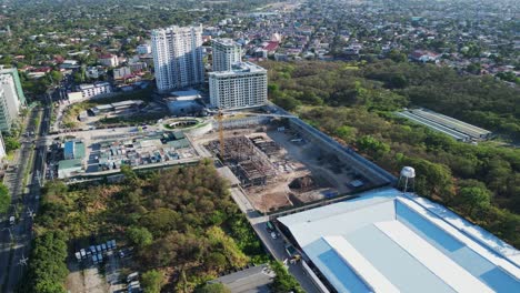 órbita aérea de un sitio de desarrollo de construcción y una grúa rodeada por el bullicioso paisaje urbano de alabang, ciudad de muntinlupa, filipinas