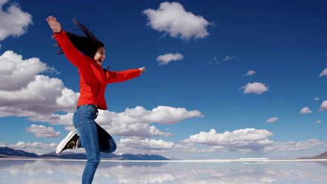 young woman jumping with joy on a reflective salt flat