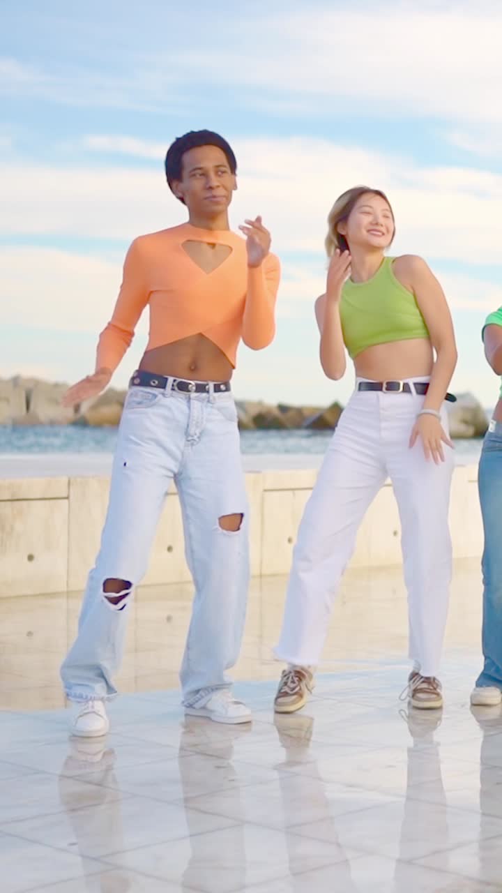 Black man and chinese woman dancing together next to sea
