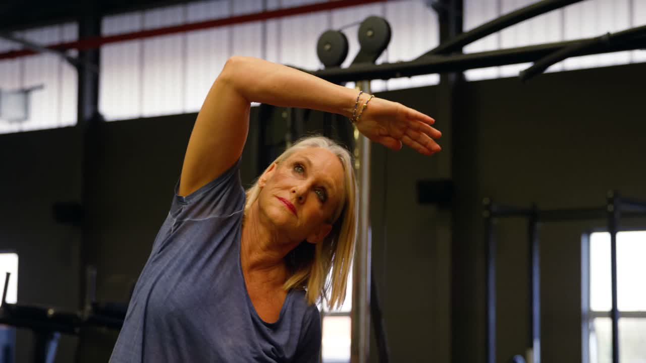 mujer de edad avanzada estirándose en el estudio de fitness 4k