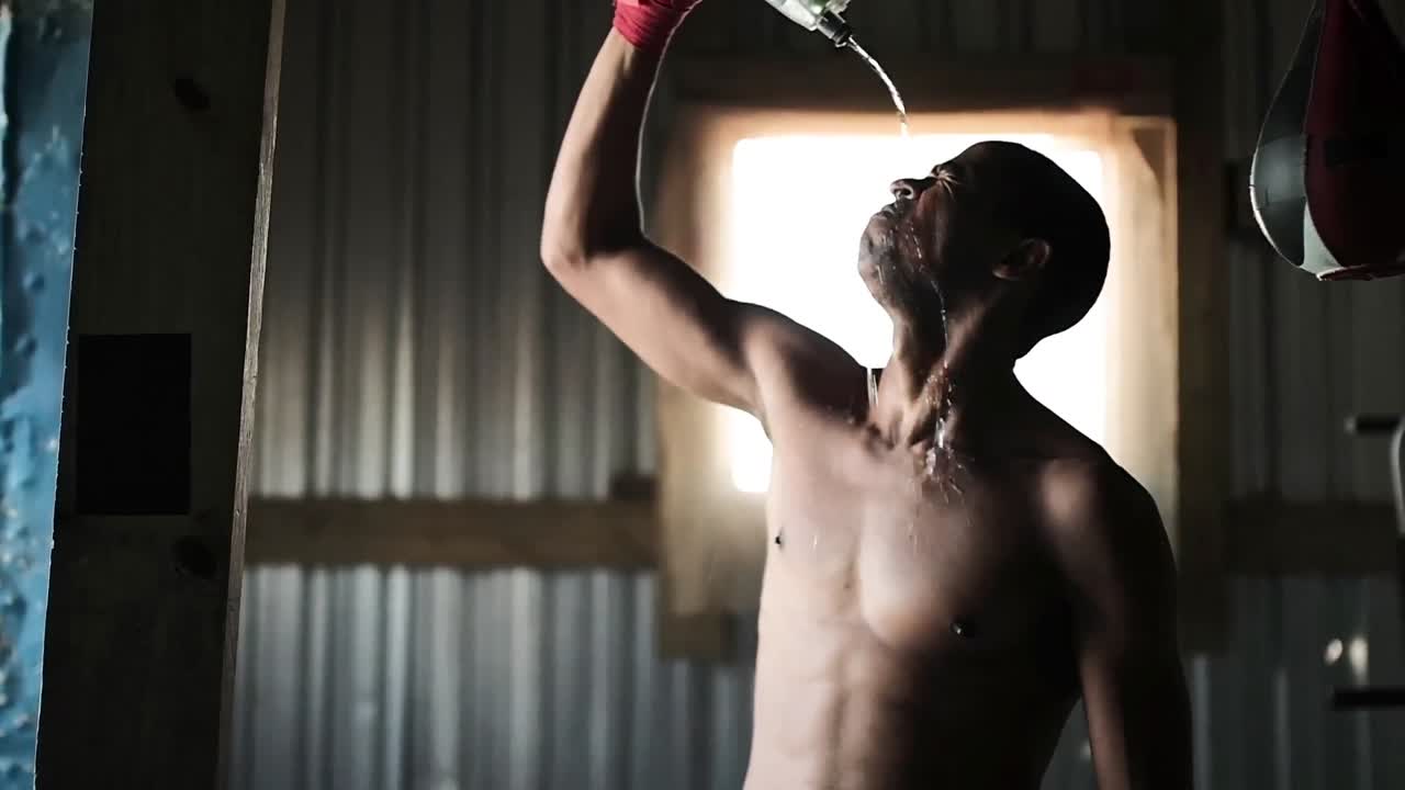 Boxer pouring water on his face in the gym
