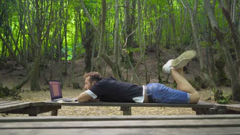 joven aventurero trabajando con una computadora portátil en la naturaleza.