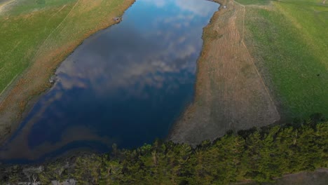 pequeño lago que refleja el cielo azul y nublado