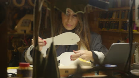 female shoemaker busy making shoe sole paper templates in specialist workshop