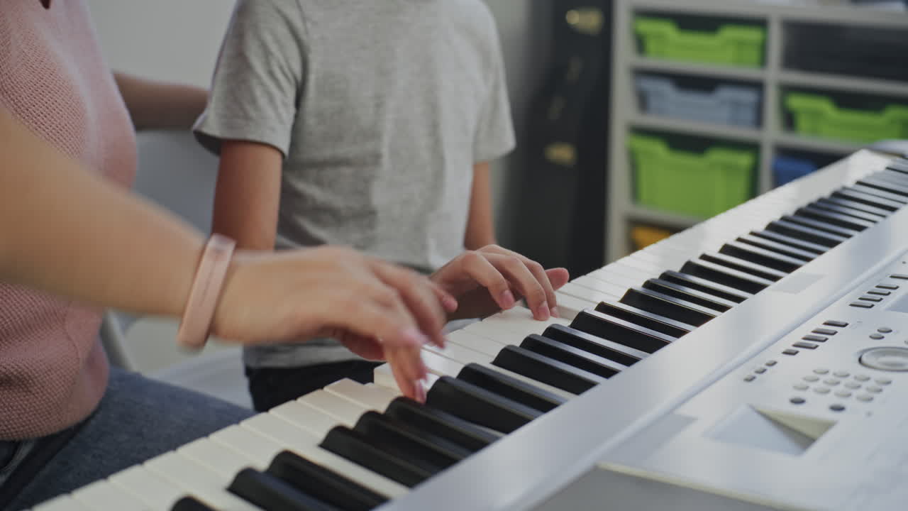 Music Teacher Guiding Primary School Boy to Play Piano in Music Class