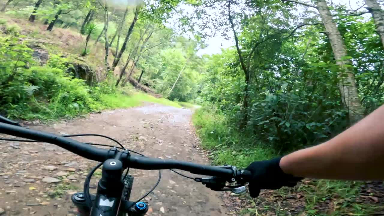 dos ciclistas andan en bicicleta por una carretera dentro de un bosque, una colina y un pueblo en guatemala, américa del norte
