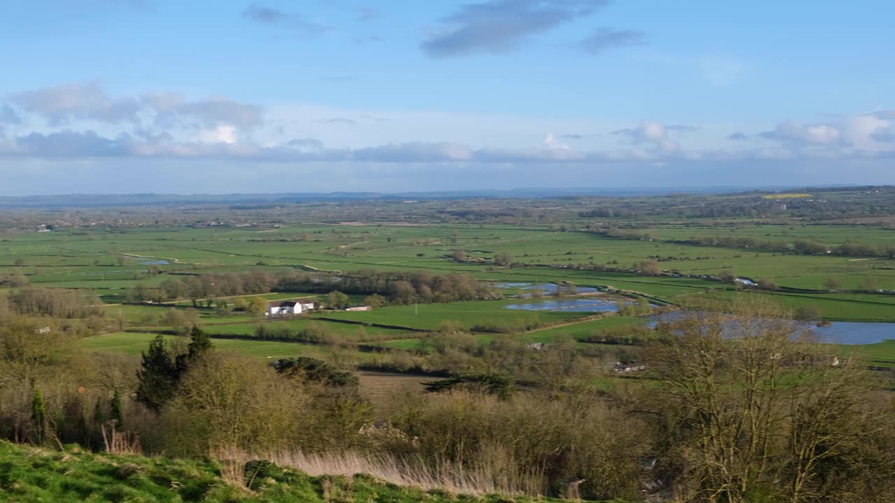 Scenic panoramic landscape over the Somerset Levels with green fields, hedges and lakes of water in Glastonbury, England UK