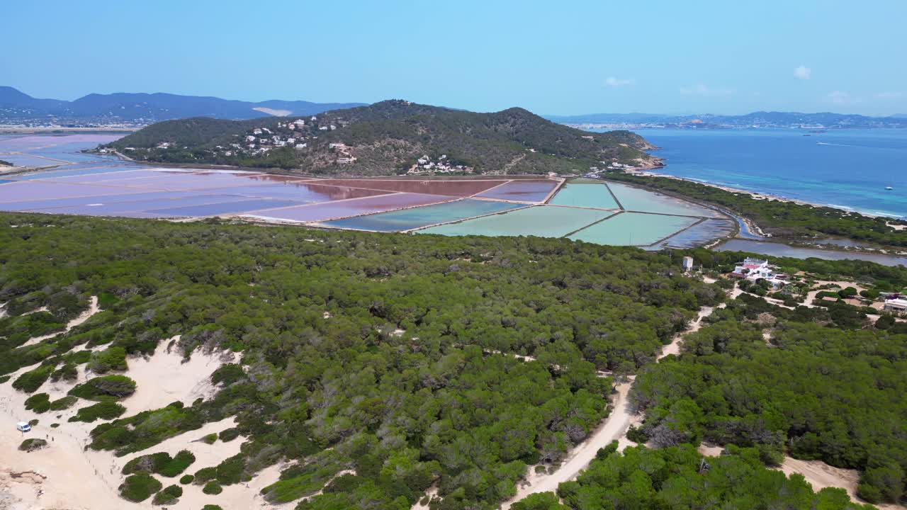 colorful salt flats of Ibiza with the Mediterranean vegetation in the foreground. Unique aerial view flight dolly left drone