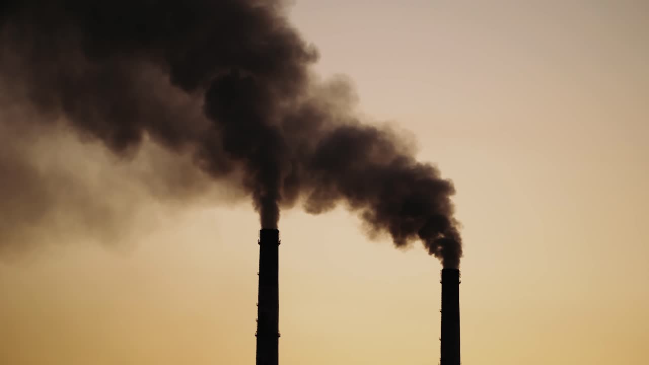Massive air pollution. Dark dense smoke coming out from huge pipes in the evening. The death of nature and life on Earth.