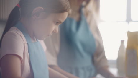 La-Niña-Está-Extendiendo-La-Masa-Con-Un-Rodillo-En-La-Cocina,-La-Madre-Y-La-Hija-Están-Cocinando-Juntas