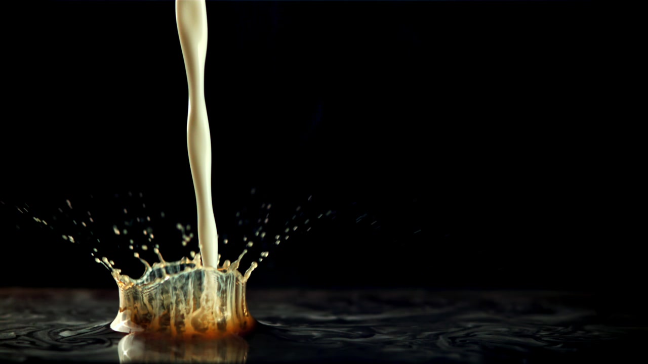 Latte che si versa e si mescola nel caffè al rallentatore