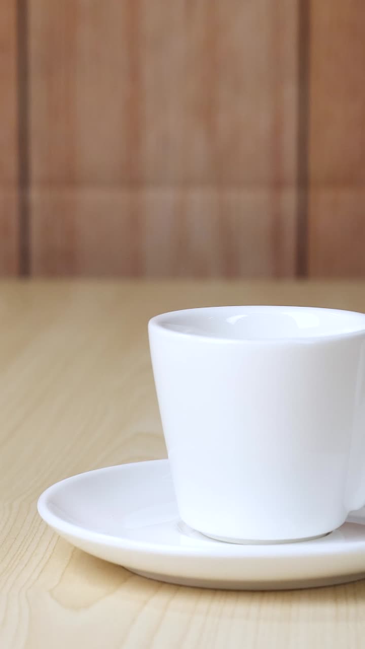한 컵이 나무 테이블 위에 앉아 있다
